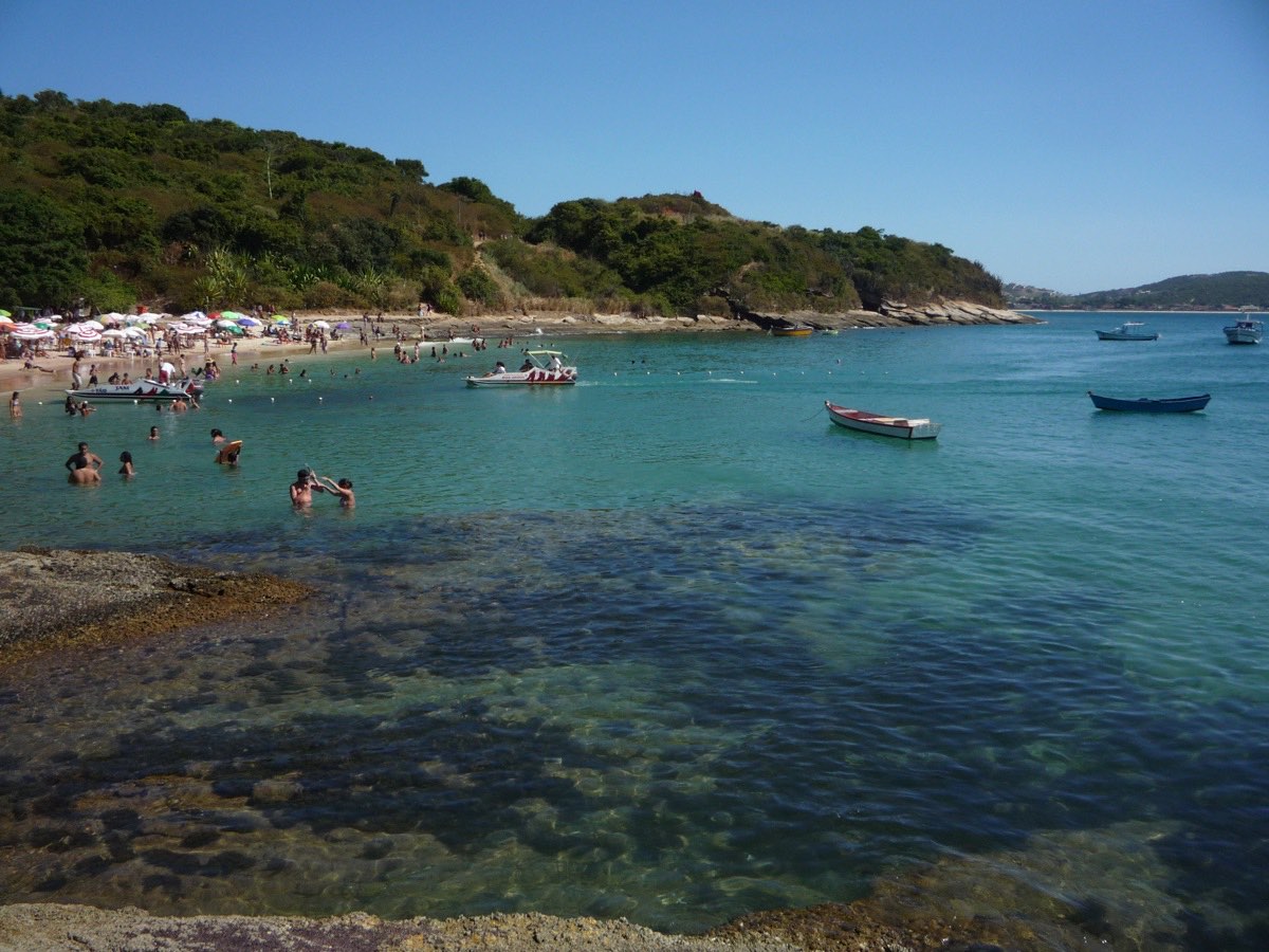 Praia de águas claras em Búzios, com barcos e banhistas