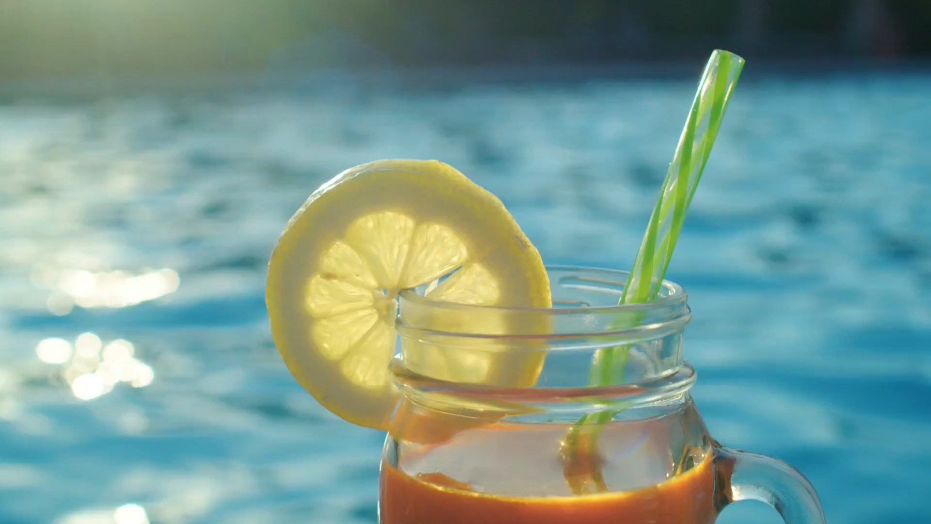 Drink com limão e canudo na beira da piscina
